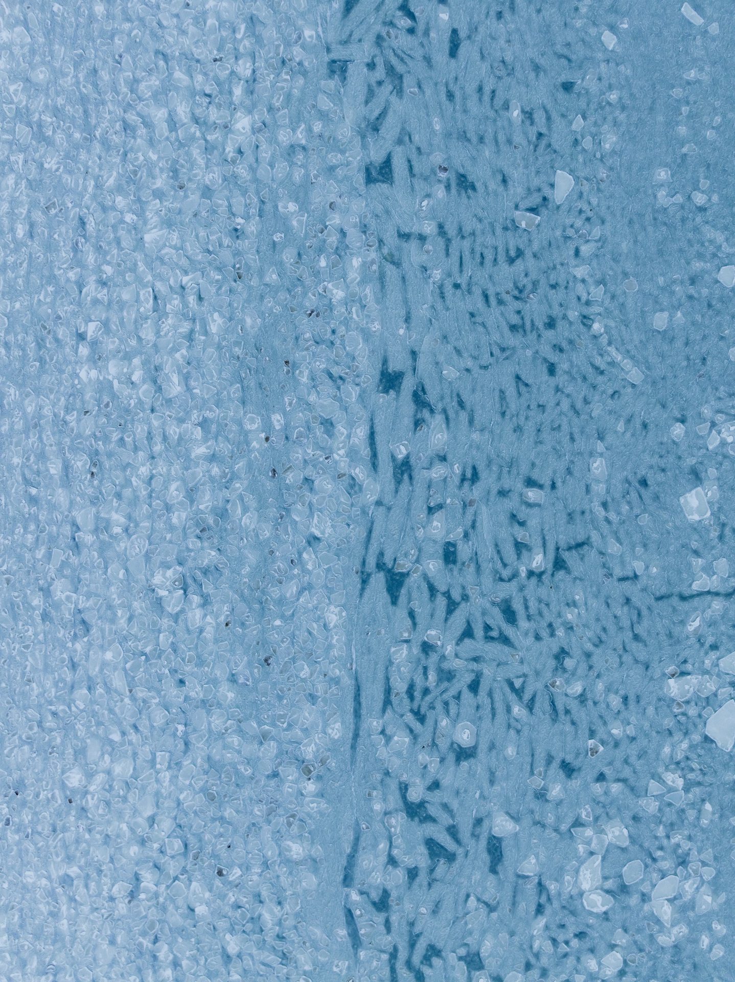 Ice crystals spread across a frozen blue surface